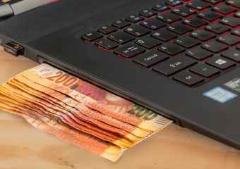 money being dispensed by a laptop