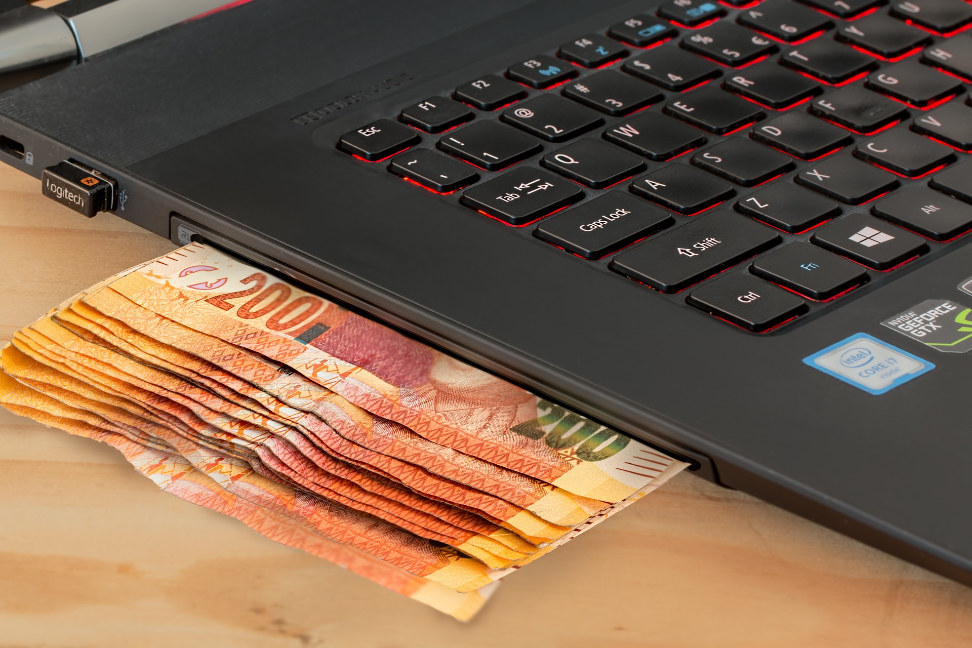 money being dispensed by a laptop